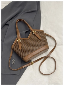 Detail of brown houndstooth woven tote bag with adjustable straps on dark suit fabric