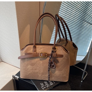 Detail der braunen Vintage-Wildleder-Tragetasche mit Riemen und metallischem Markenlogo