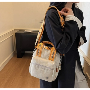 Détail du sac bandoulière en nylon blanc cassé avec double fermeture et sangle jacquard