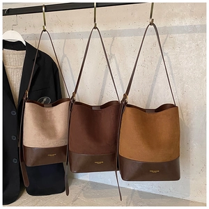 Detail of suede bucket bags in earth tones with contrast stitching and long straps