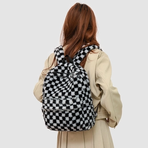 Detail of plush black and white checkerboard backpack showing soft texture and straps
