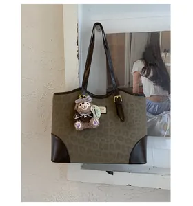 Dettaglio della borsa shopper leopardata con angoli in pelle e un grazioso ciondolo a orsetto