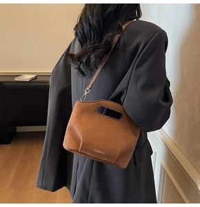 Detailed close-up of brown suede bucket bag with gold hardware and logo on model