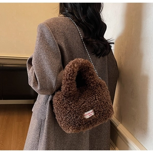 Dettaglio borsa di peluche marrone con tracolla a catena e etichetta in tessuto