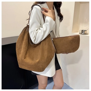 Detail view of large brown suede tote bag and matching inner pouch on a model
