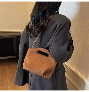 Detail view of brown suede bucket bag with cut-out handle and adjustable shoulder strap