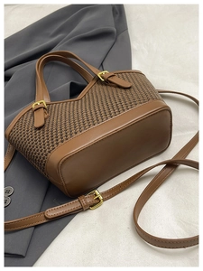 Detail view of brown houndstooth tote bag featuring smooth leather handles and gold metal buckles