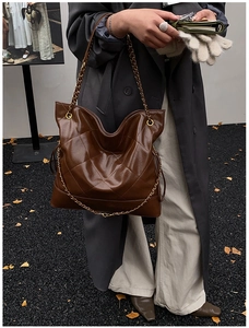 Street style shot of large quilted tote bag in dark brown with gold chain strap