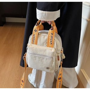 Détail du mini sac en nylon blanc cassé avec bretelles fleuries orange et poche zippée