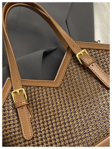 Close-up of woven texture and brown leather strap with gold buckle on a tote bag