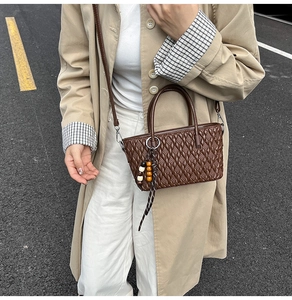 Detailansicht der braunen Bucket Bag mit Webmuster, Holzperlenanhänger und Tragegurt