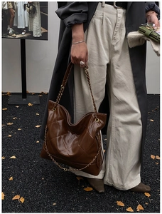Detailed view of the large quilted tote bag in glossy brown leather with gold chain strap