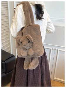 Détail d'un sac cabas en peluche marron avec une mascotte d'ours en peluche attachée