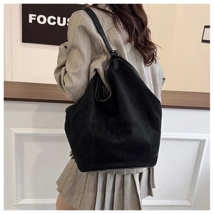 Detailed back view of a model wearing a large black suede tote bag with leather straps