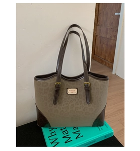 Dettaglio della borsa tote leopardata con manici in pelle marrone e logo metallico