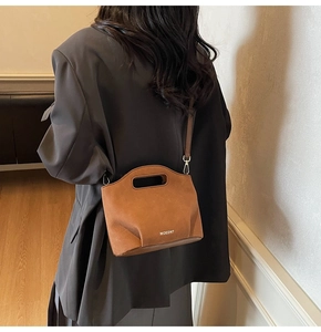 Macro detail of the MOEDNT brand logo on the brown suede minimalist bucket bag