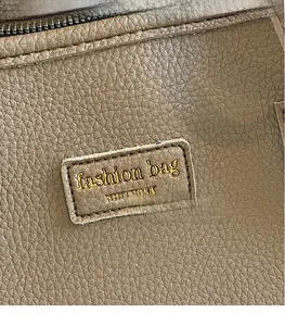 Detail of brown lychee grain leather with gold-stamped logo on the tote bag