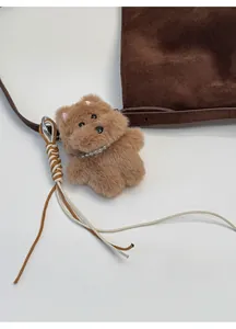 Pendentif chien en peluche avec collier de perles et badge sur sac en daim marron