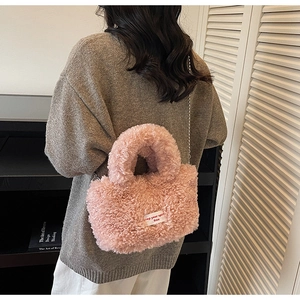 Dettaglio borsa a secchiello rosa in peluche con tracolla di perle e etichetta