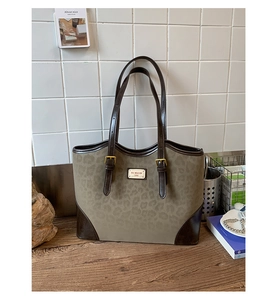Dettaglio della borsa tote leopardata con finiture in pelle marrone e fibbie d'oro