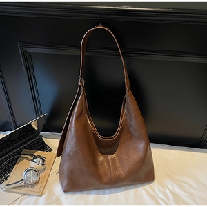 Detail view of brown wax leather tote bag with laptop and books for a lifestyle look