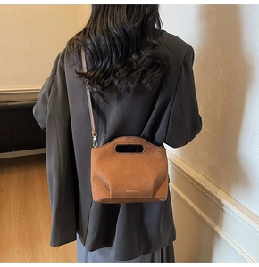 Detail view of brown suede bucket bag with cutout handle and embossed MOEDUT logo