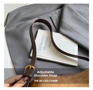 Detail of adjustable leather strap and brass buckle on a brown suede bucket shoulder bag