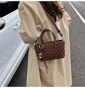 Detail der Webstruktur einer dunkelbraunen Beuteltasche mit Vintage-Perlenanhänger
