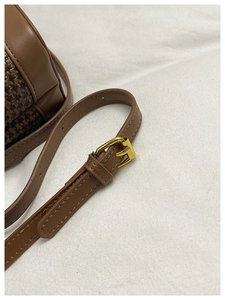 Detailed close-up of brown leather strap with golden metal buckle and neat stitching