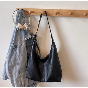 Detail of black pebbled leather Hobo shoulder bag hanging on a wooden coat rack