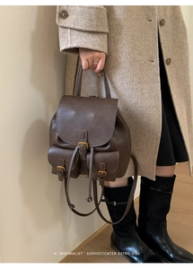 Detail eines dunkelbraunen Vintage-Rucksacks aus Kunstleder mit goldenen Metallschnallen