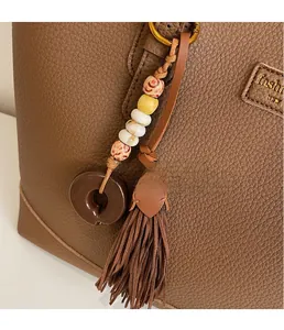 Detailed view of a handmade beaded bag charm with premium leather tassels on a tote bag