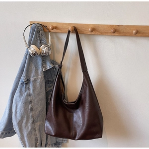 Detailed texture of dark brown PU leather hobo bag hanging on a wooden hook