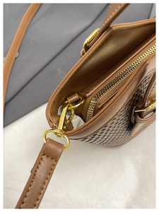 Detail of golden metal zipper and woven texture on brown leather commuter tote bag