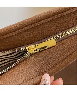 Macro shot of gold metal zipper and lychee textured leather on a brown tote bag