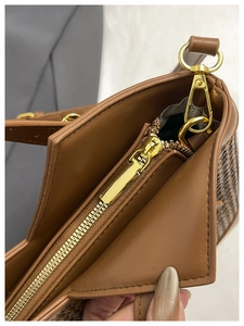 Detail of brown leather tote with houndstooth fabric and gold metal zipper hardware