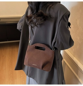 Deep brown matte suede bucket bag with cut-out handle and metallic logo on model