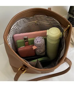 Interior view of large brown leather tote bag with striped lining and storage capacity