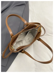 Top view of brown tote bag interior showing gray lining, zipper pockets, and compartments