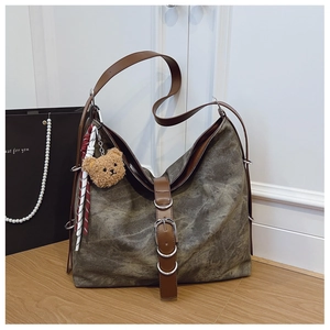 Detail view of large olive green vintage canvas tote bag with plush bear charm and leather straps