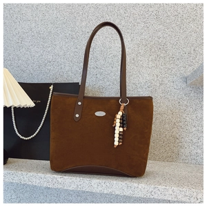 Détail d'un grand sac cabas marron foncé en suédine avec logo métal et perles en bois