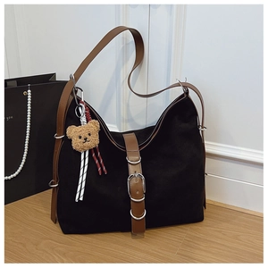 Detail of vintage tote bag with metal buckle and a cute brown plush bear charm