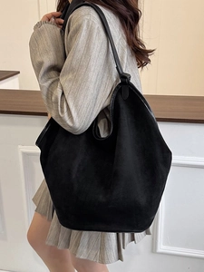 Minimalist large black hobo shoulder bag in matte suede with leather trim on a model
