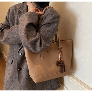 Detail of brown litchi pattern leather tote bag with retro tassel and wooden ring