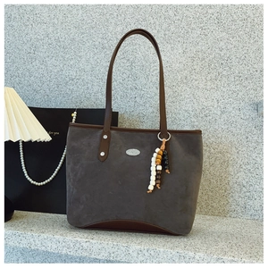 Détail d'un grand cabas en daim gris avec finitions en cuir marron et gland à perles