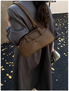 Detail of dark brown retro bowling bag with textured leather on casual shoulder outfit