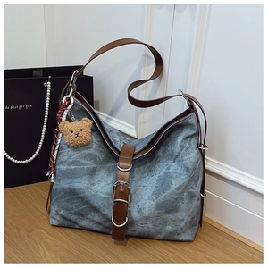 Detail of blue marble-texture canvas tote bag with brown leather strap and bear charm