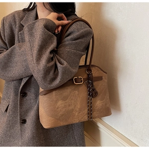 Nahaufnahme der braunen Vintage-Ledertasche mit Metallschnalle und gewebtem Anhänger