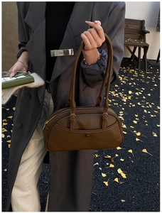Detail of dark brown leather bowling bag with lychee texture and long shoulder handles