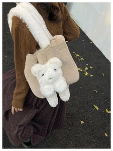 Gros plan d'un grand sac fourre-tout beige en peluche avec un petit ours porté dehors